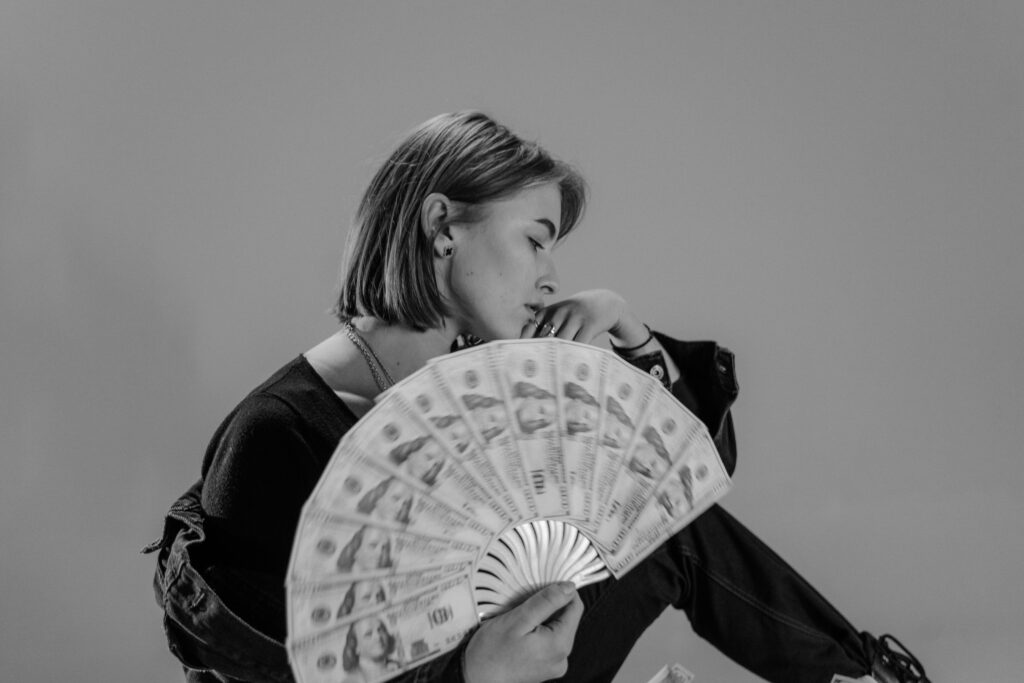 Woman holding hand fan made of paper money
