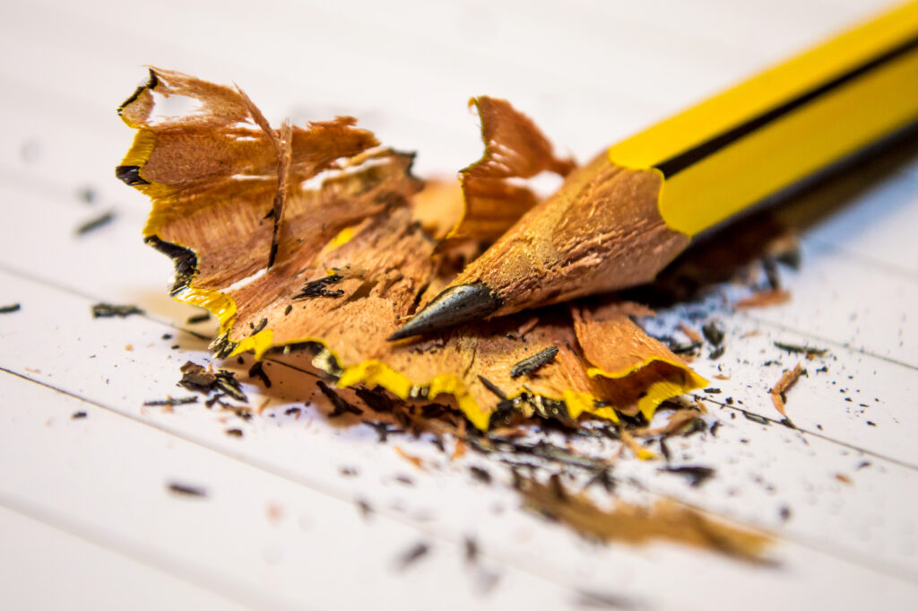 Yellow black pencil sharpened above the white paper in macro photography